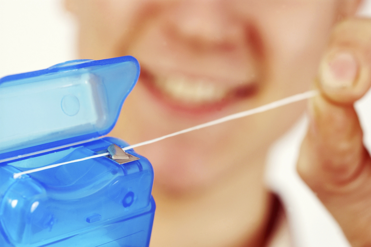 A woman pulls out floss from a container.