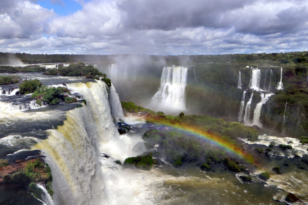 a rainbow in the middle of Iguazu Falls waterfalls in brazil