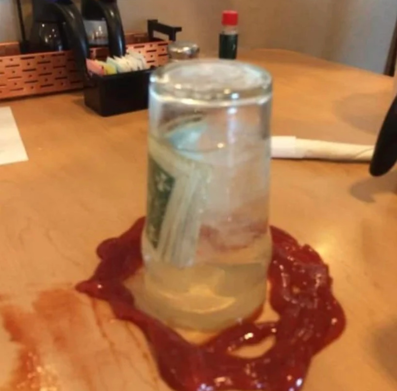 restaurant customers leave tip in a flipped over glass full over water in a circle of ketchup