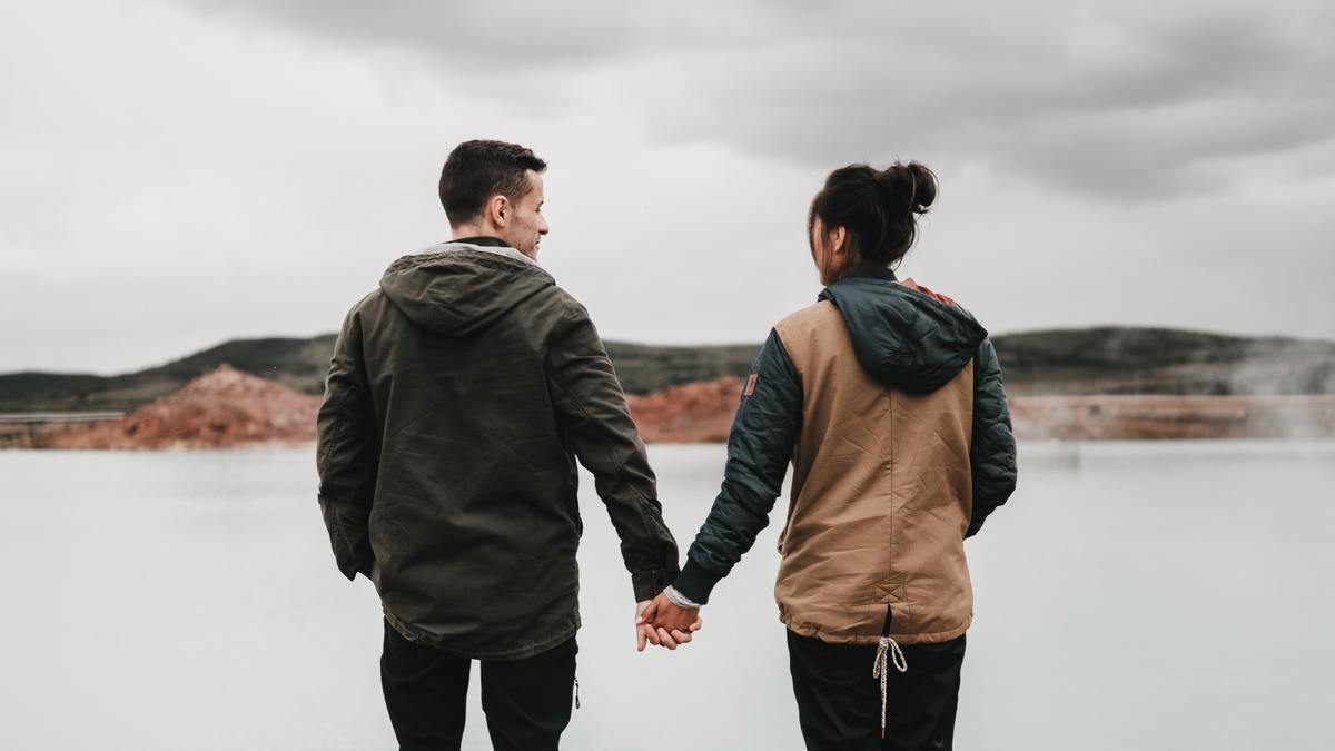couple facing away form camera looking at body of water