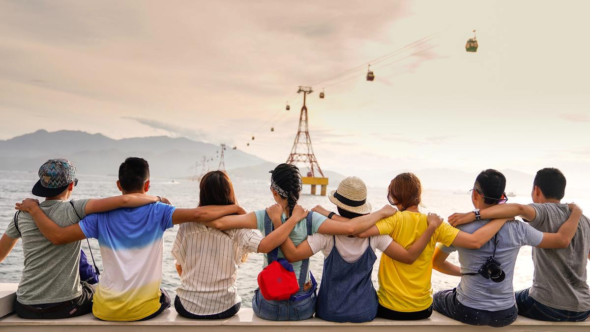 group of friends sitting on pier with arms linked looking away