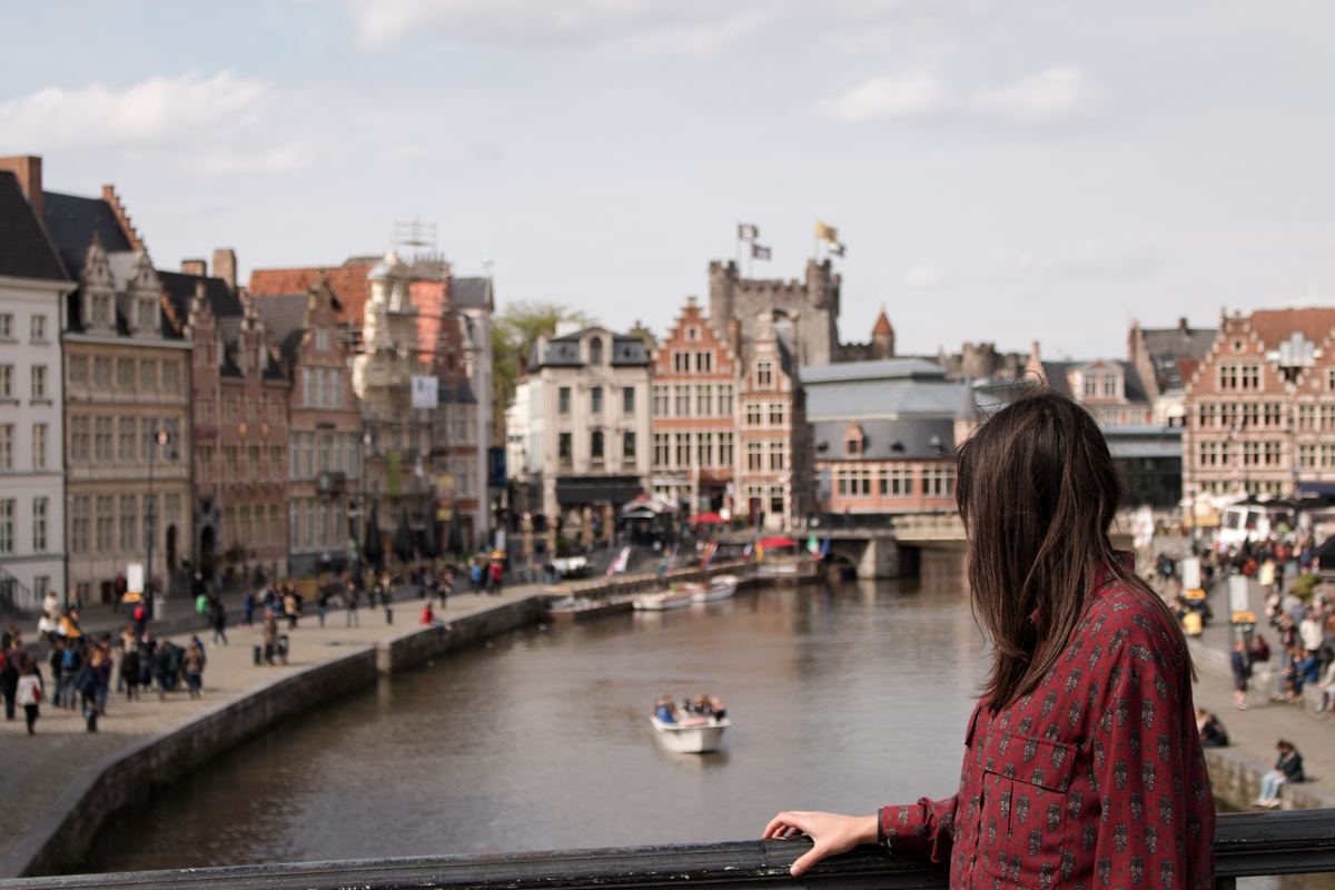 a girl standing on a bridge overlooking ghent, belgium