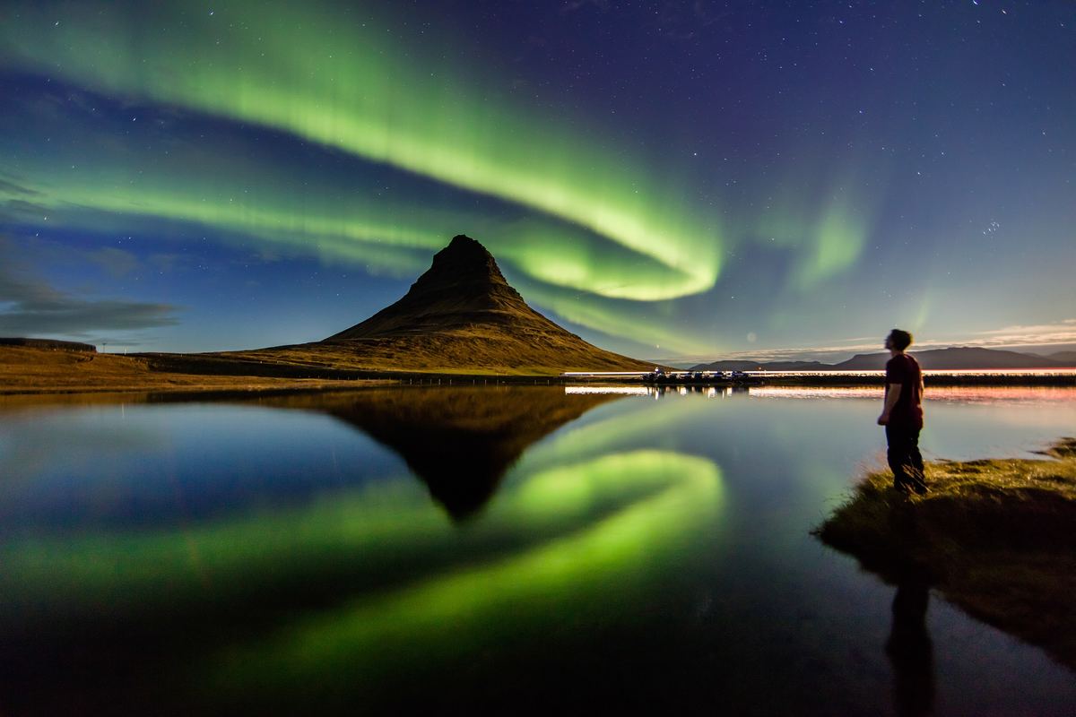 a man looking up at the northern lights in iceland