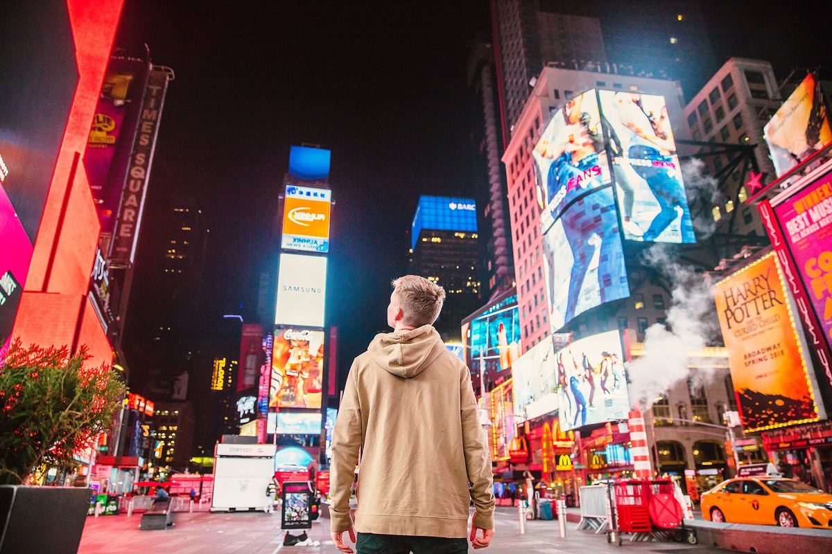 a boy standing in times square in new york city