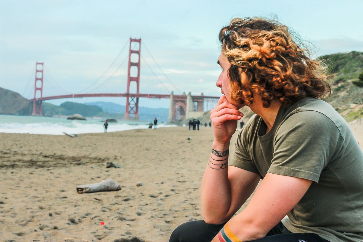 a man sitting on the beach looking at the golden gate bridge in san francisco