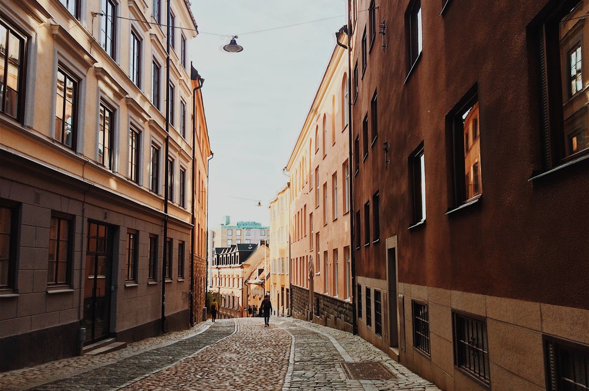 a far away shot of a person walking in between buildings in stockholm, sweden