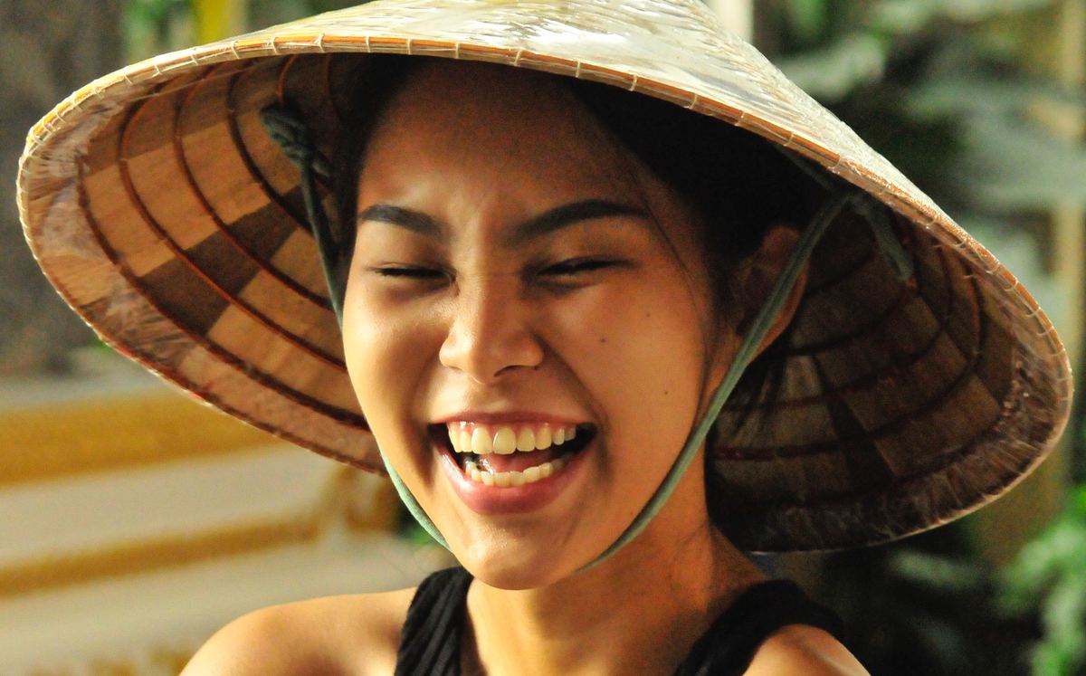 a woman wearing a tradiional thai hat smiling in thailand