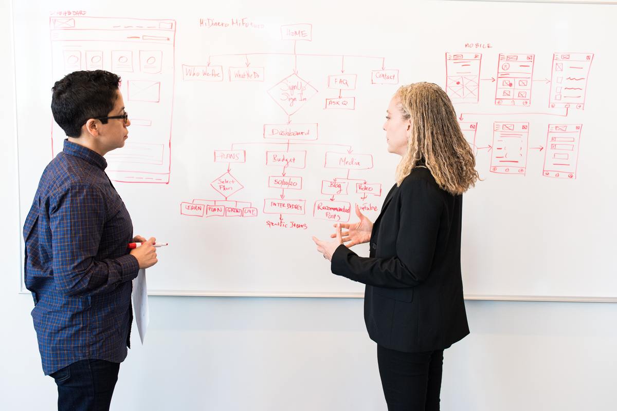 man and woman talking in front of whiteboard