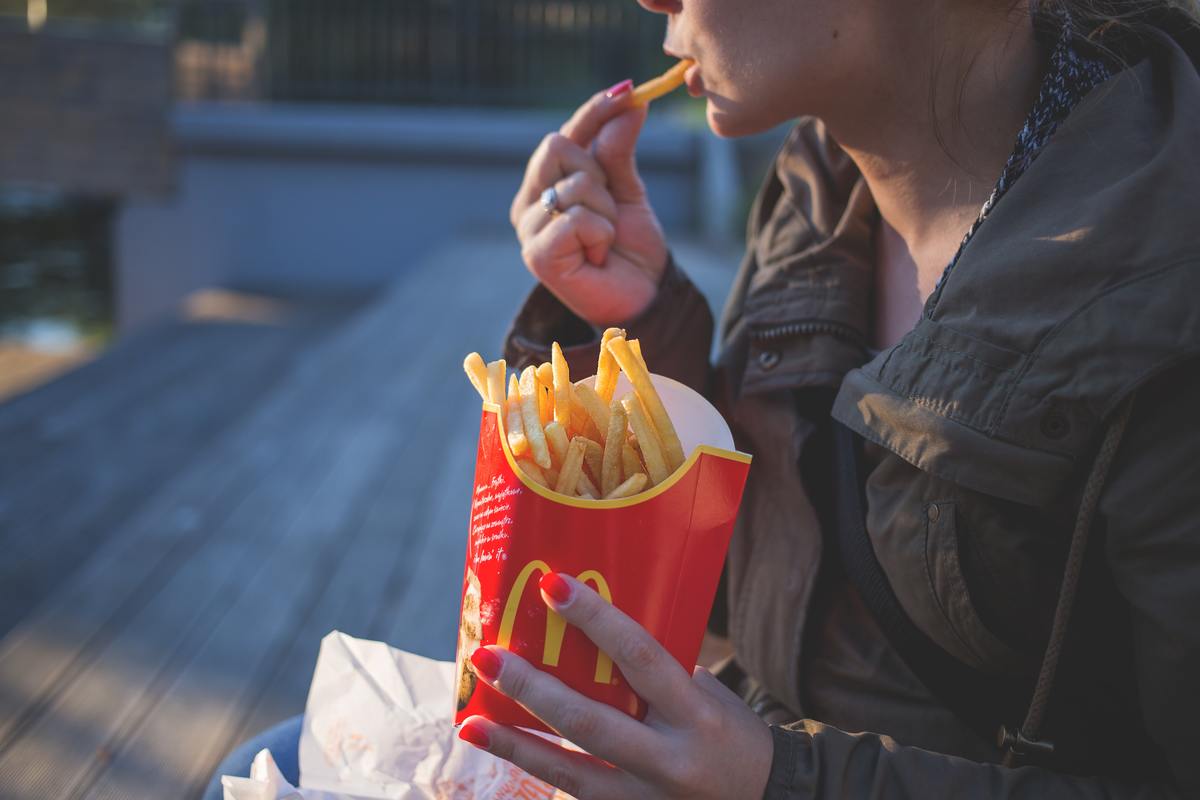 woman sitting outside eating large mcdonald's fries