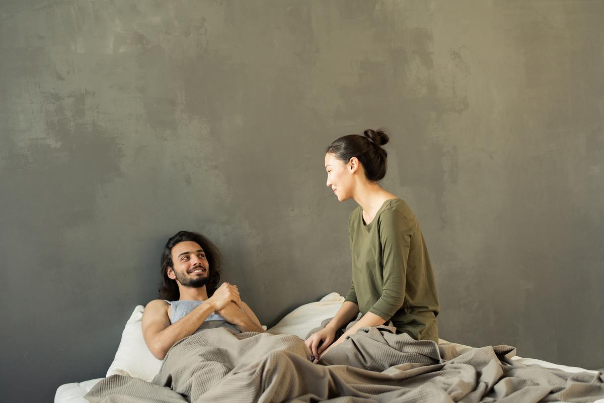 woman and man sitting in bed, man smiling