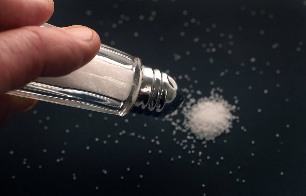 A person pours salt from a shaker.