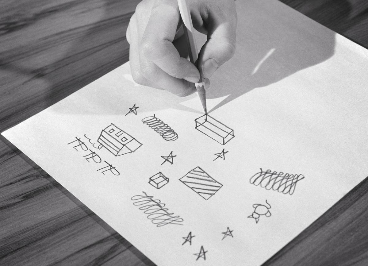 A person draws random shapes on a piece of paper.