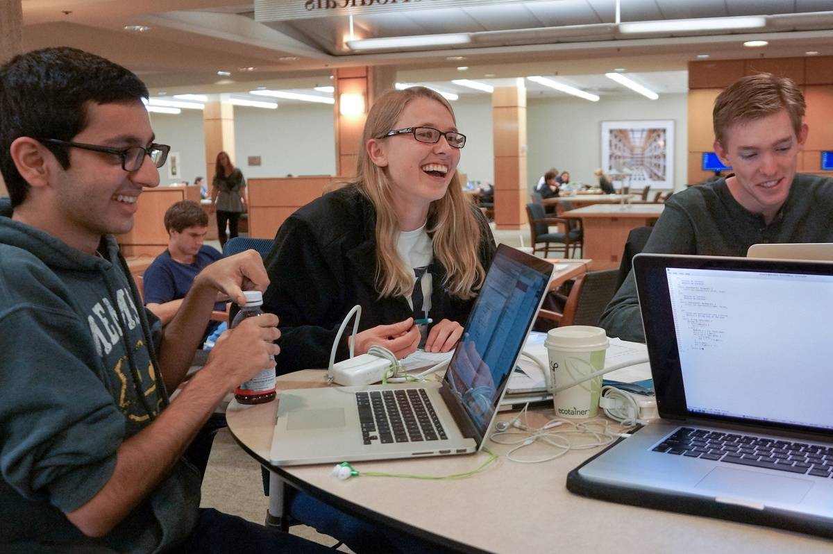 Three students study together in a library.