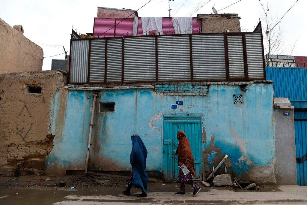 two people walking in a worn down area of Kabul, Afghanistan