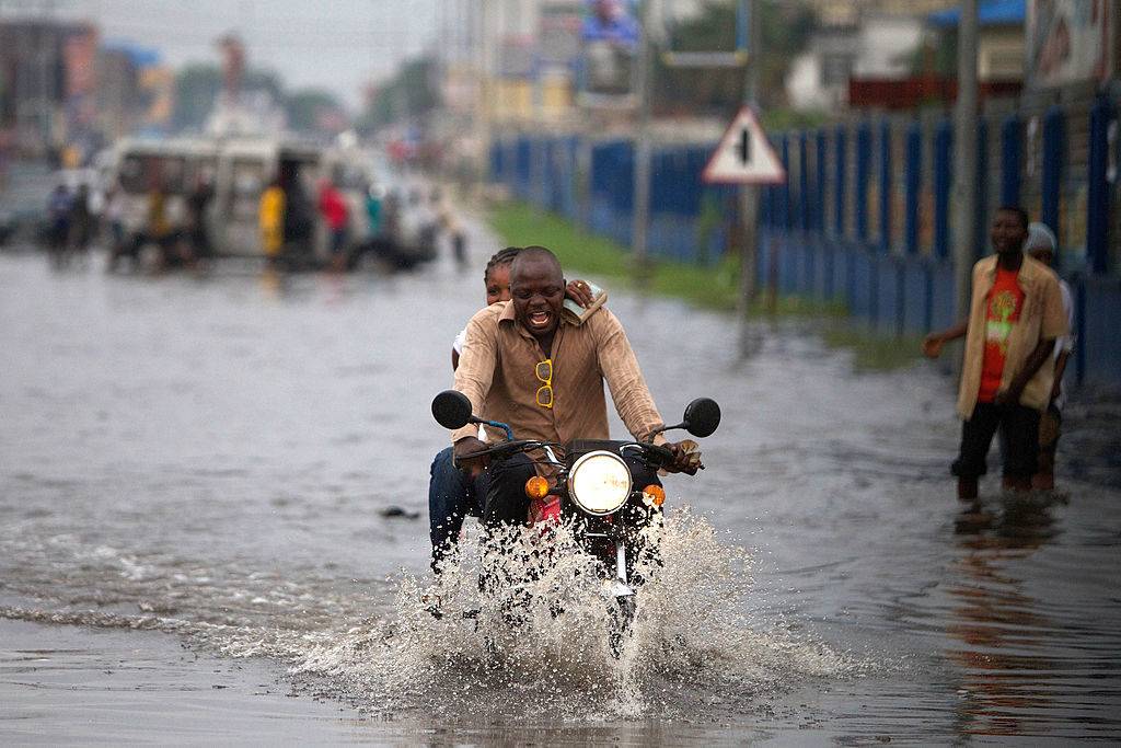 people riding a motorcycle in a flooded street in Kinshasa, The Democratic Republic Of Congo