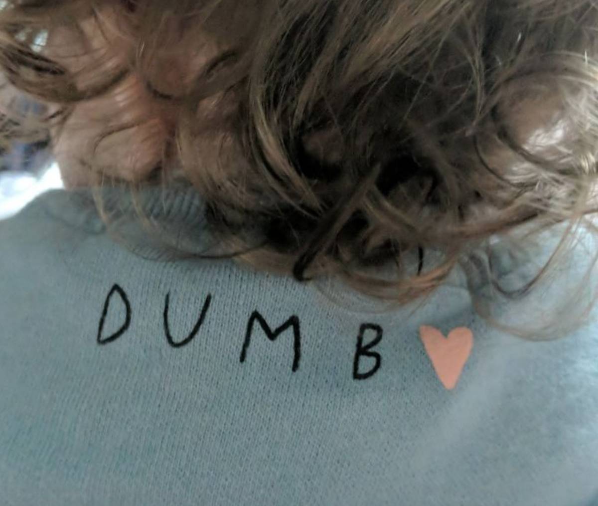 back of baby's shirt says dumb with a heart next to it