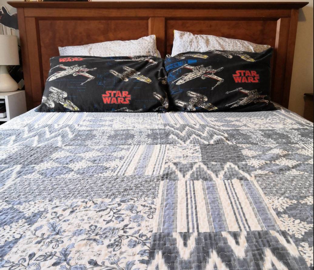 bed with tasteful quilt and clashing black and red star wars pillow cases