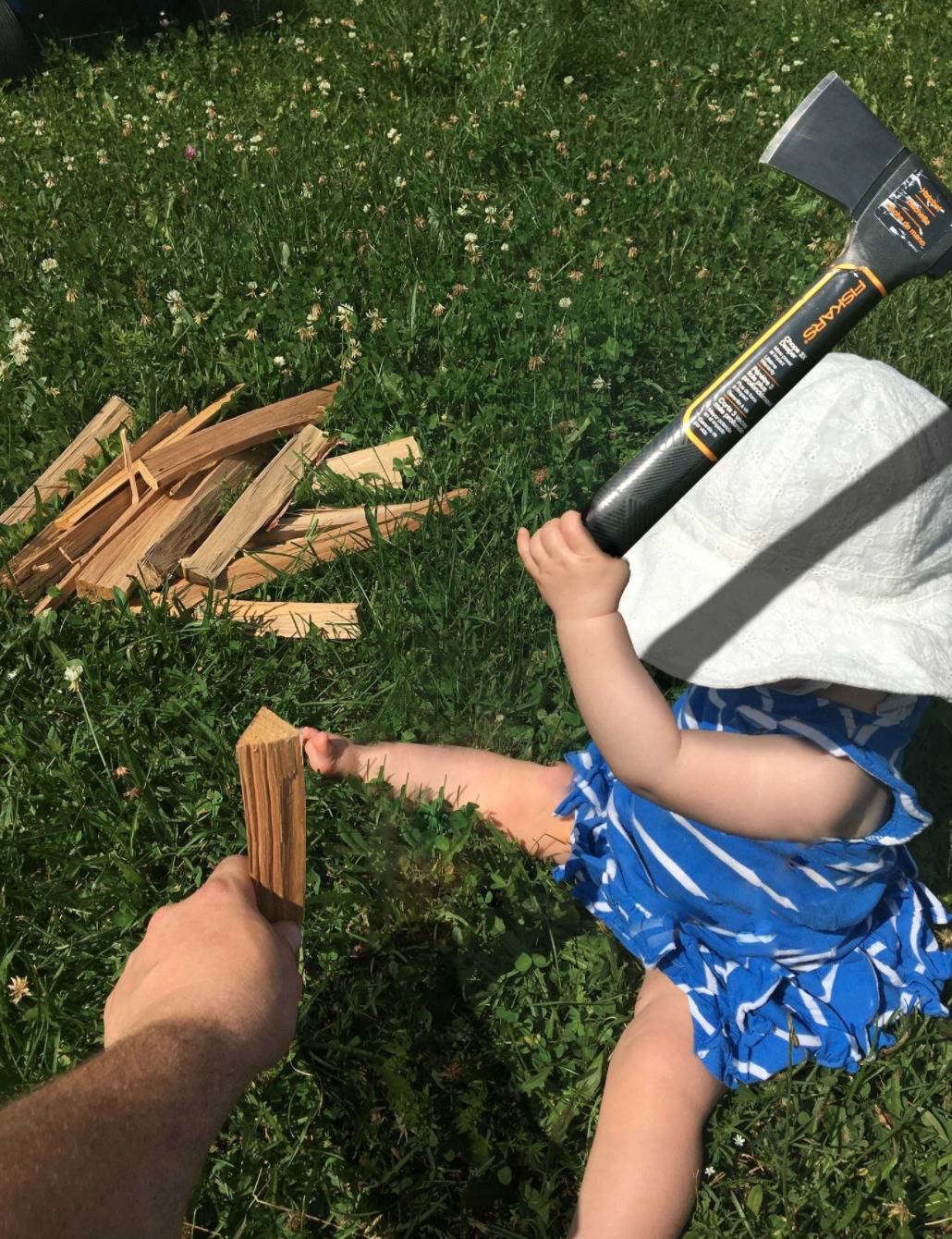baby holding an ax to split a piece of wood