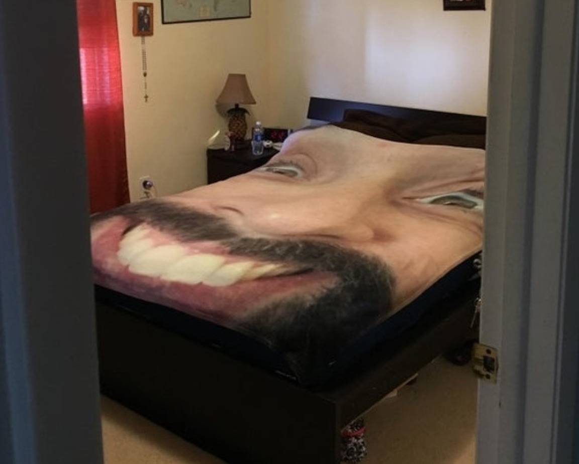 bed covered in blown up photo of man's face