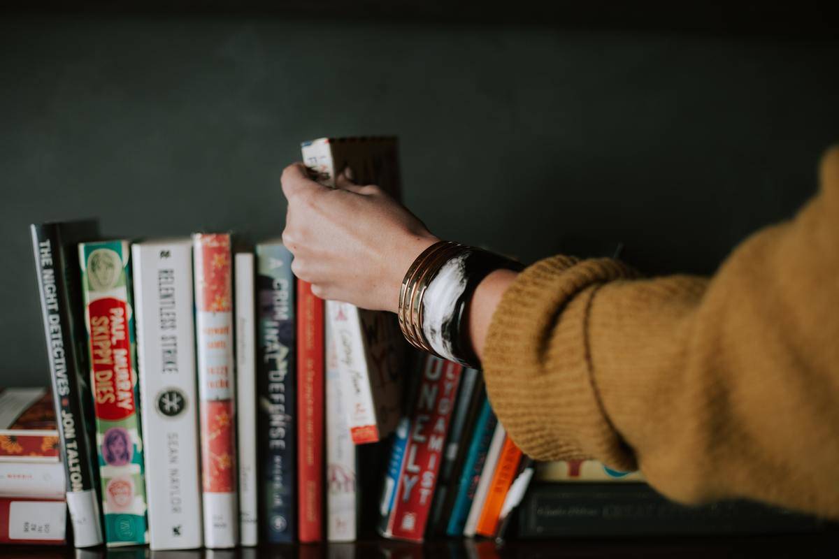 person choosing book from shelf
