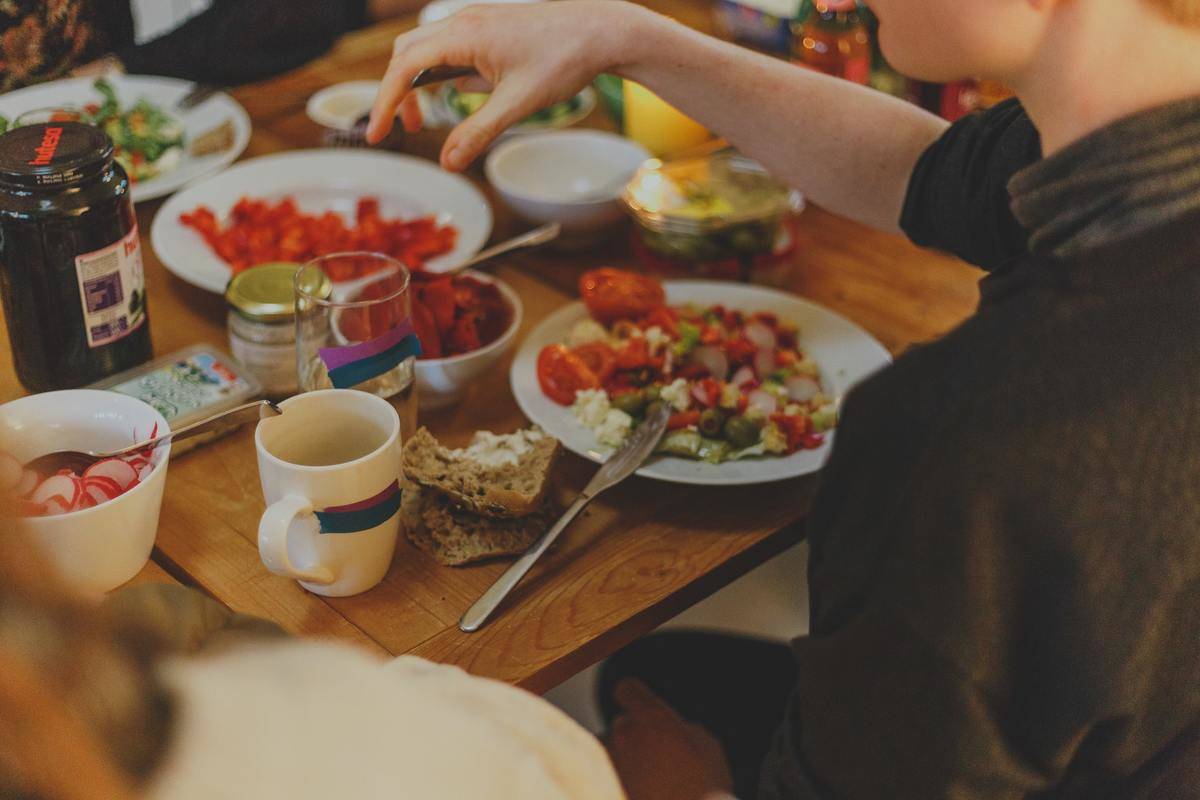 A woman selects healthy food from a dinner table.