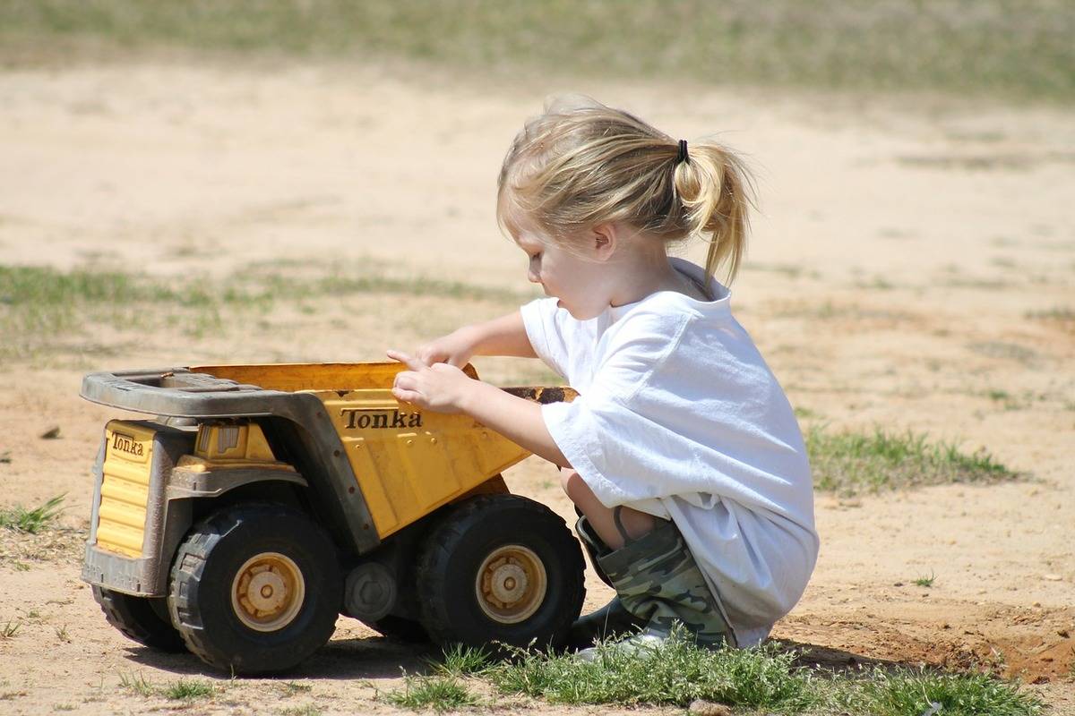 A child plays in dirt with a toy truck. 