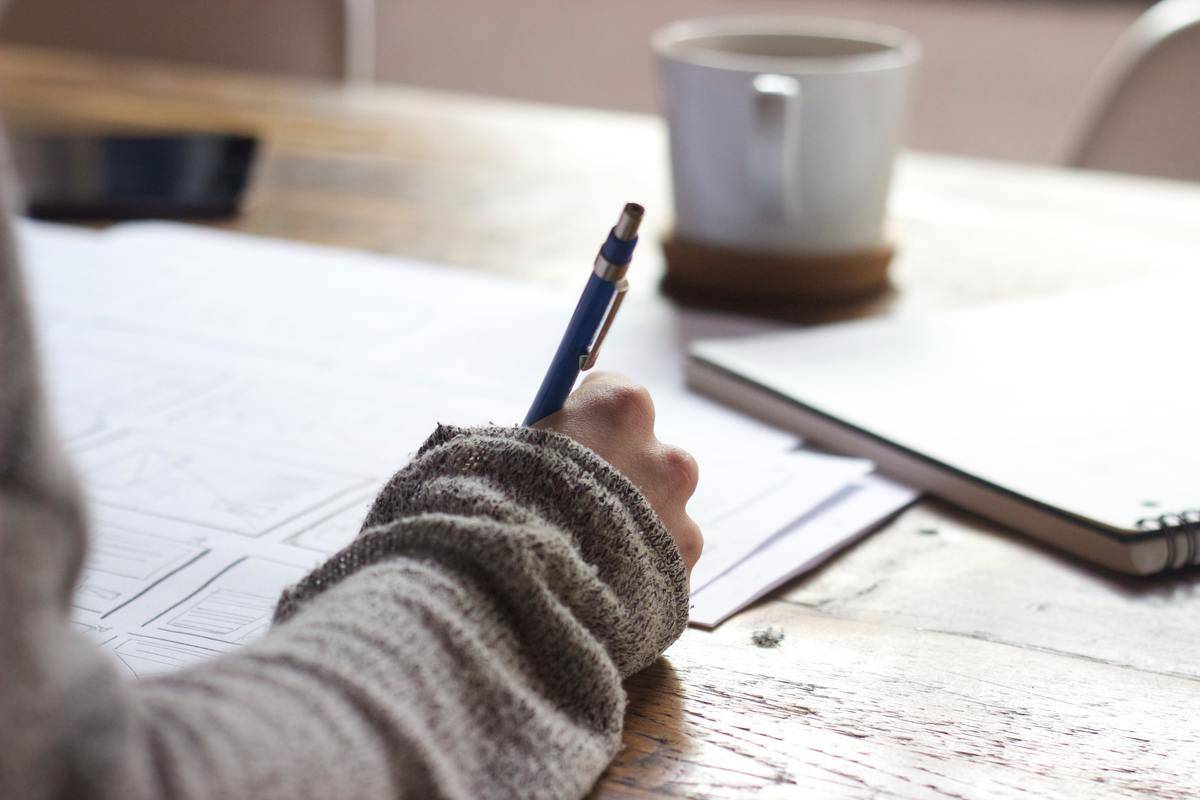 woman sitting at desk writing in note book