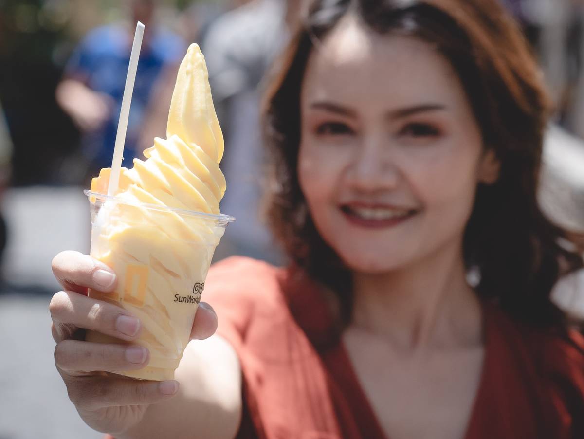 A woman holds out an ice cream cup.