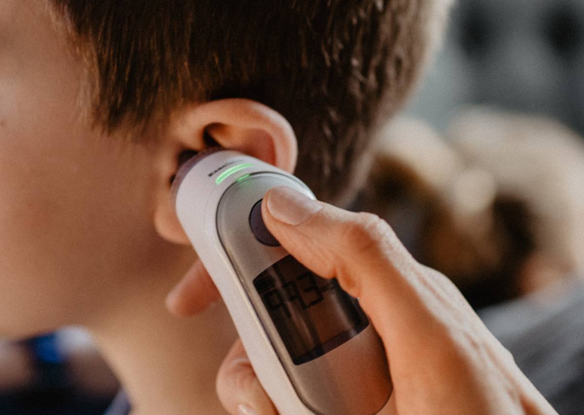 A man gets his temperature checked with a thermometer in his ear. 