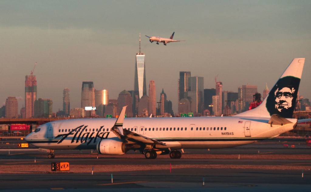 An Alaska Airlines airplane passes by the skyline of lower Manhattan in New York City