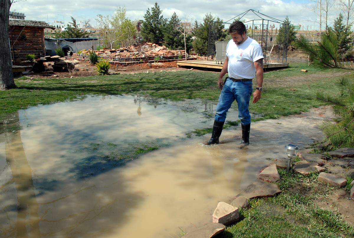 A man wades through his flooded lawn.