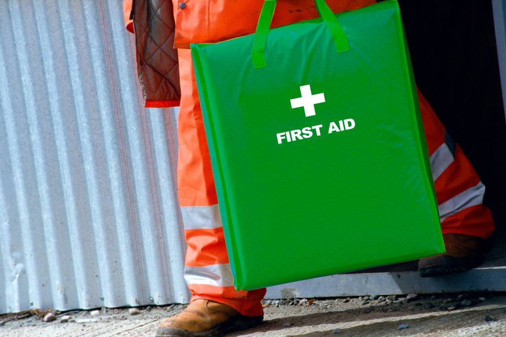 worker holding a green first aid kit