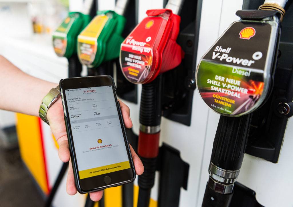 someone holding a phone in front of gas pumps
