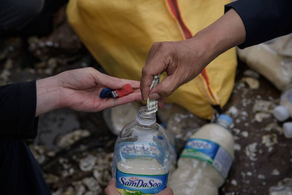 people putting money inside a water bottle