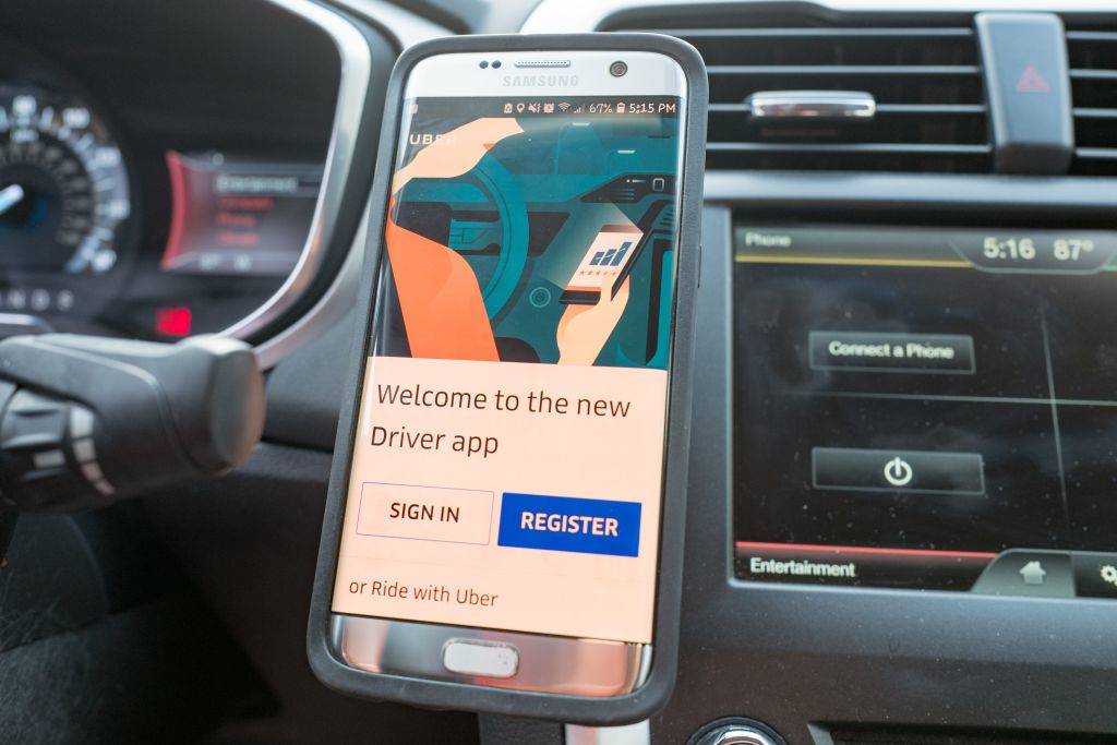 Close-up of a smartphone displaying the Uber driver app installed on a magnetic dash mount