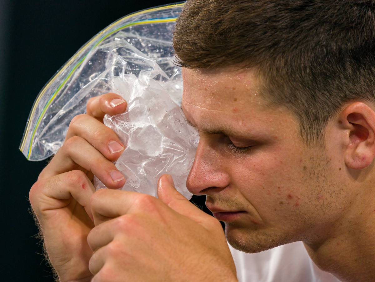 A Polish athlete treats his right eye with ice pack.