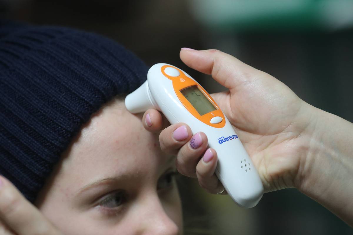 A person measures a child's temperature with a digital thermometer.