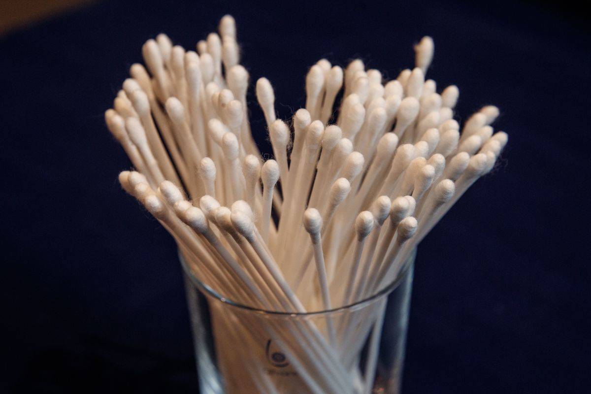 A clear container holds cotton swabs.