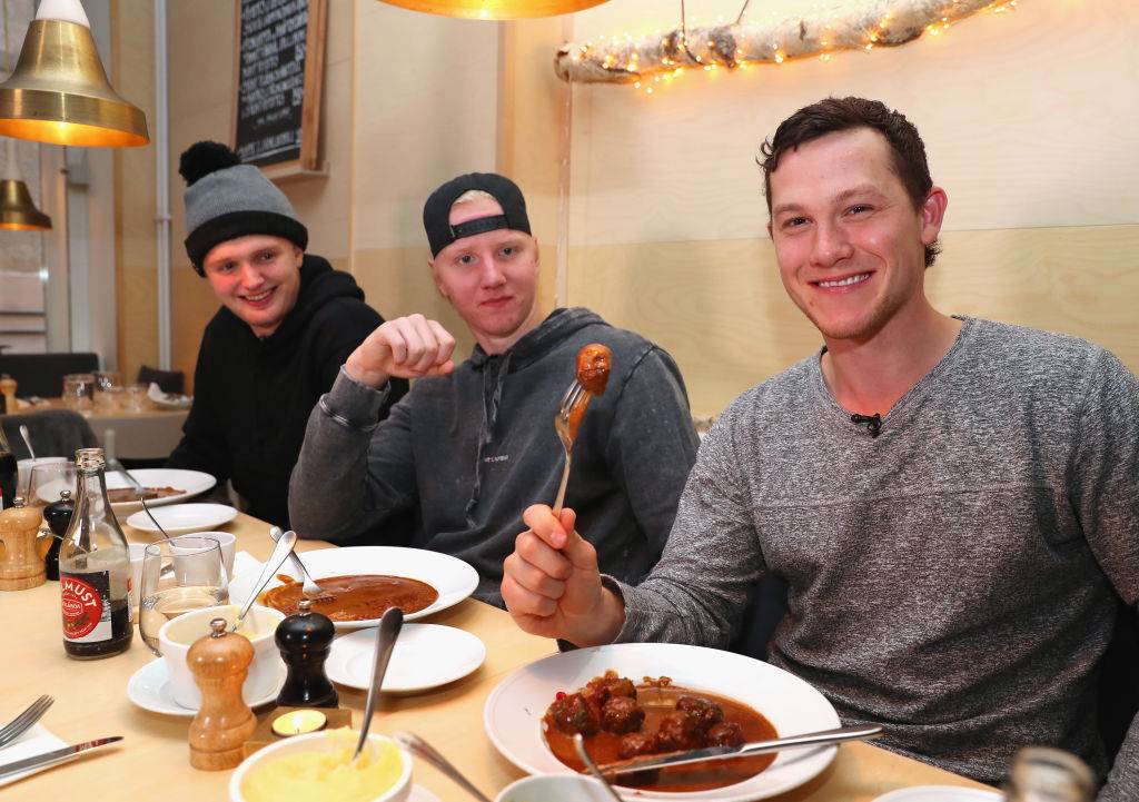 three young men eating Köttbullar