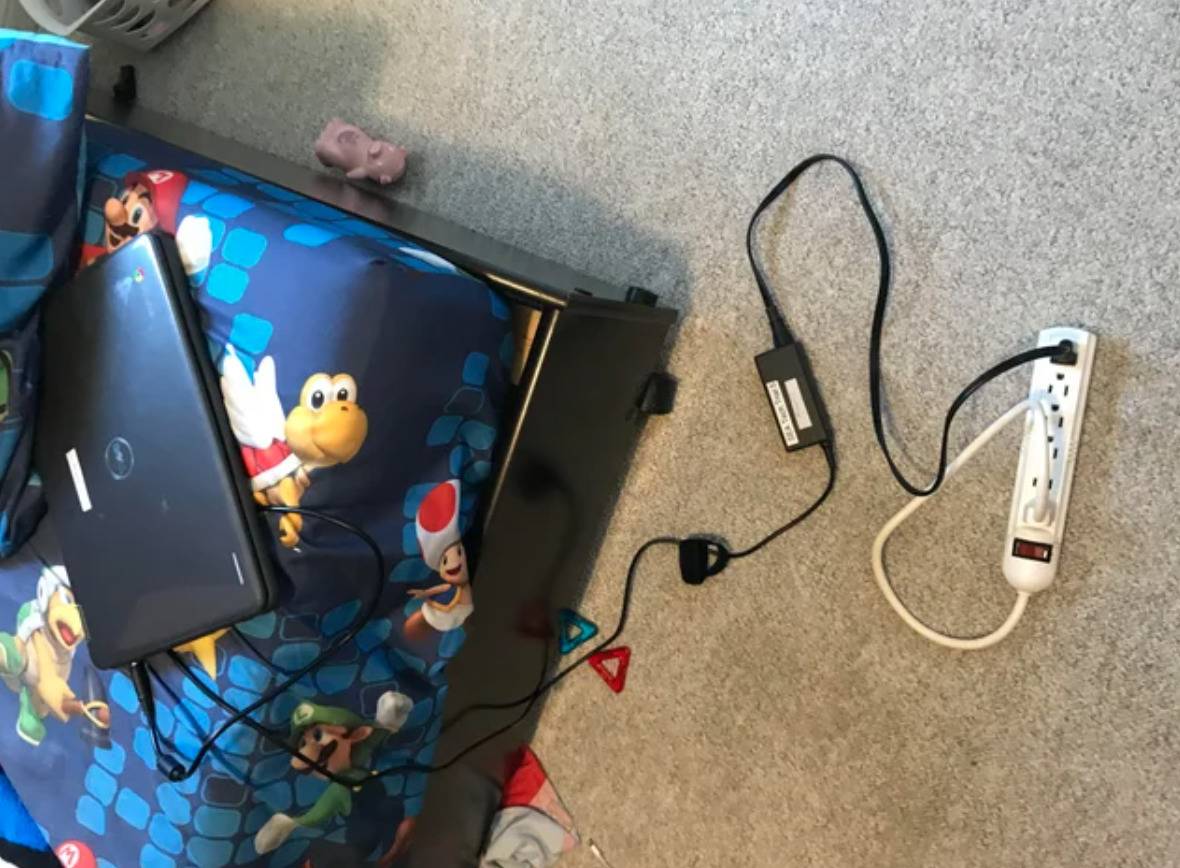 person with laptop plugged into a power bar that is also plugged into itself