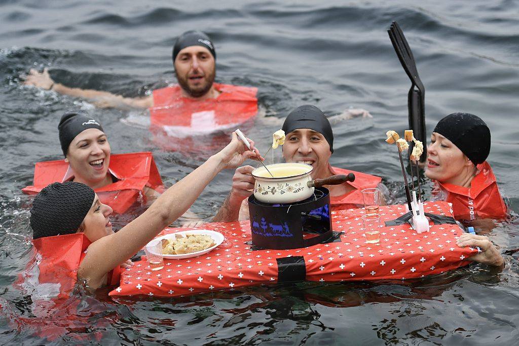 People eating a cheese fondue as they swim