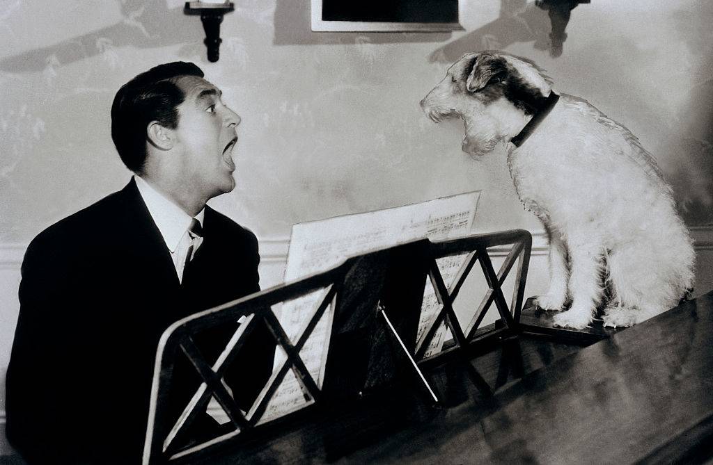 Cary Grant singing with Skippy the famous movie dog at a piano