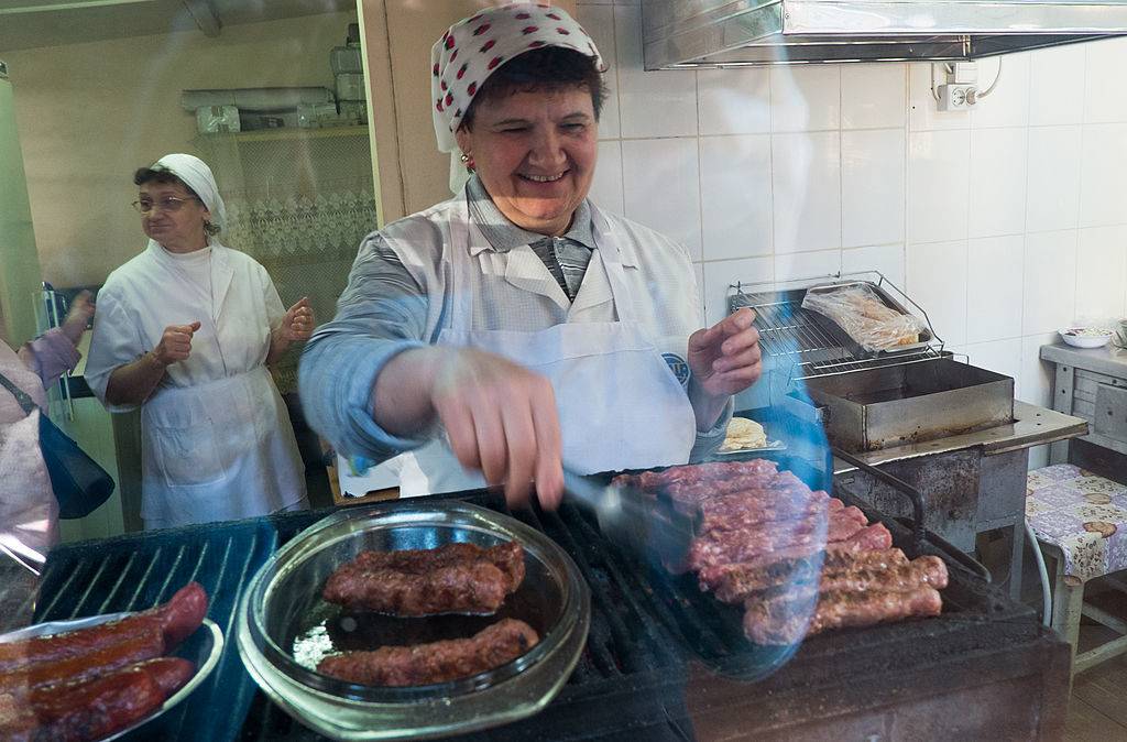 a old romanian woman cooking mititei sausages