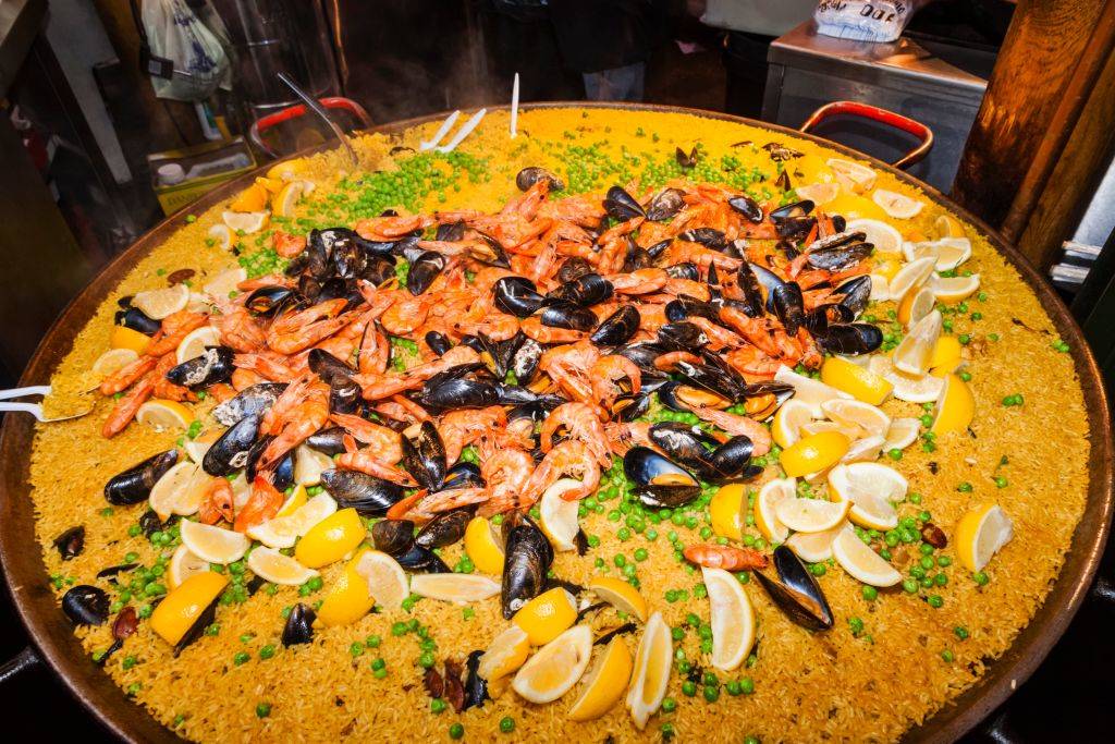 paella with rice, seafood, peas, and lemon slices