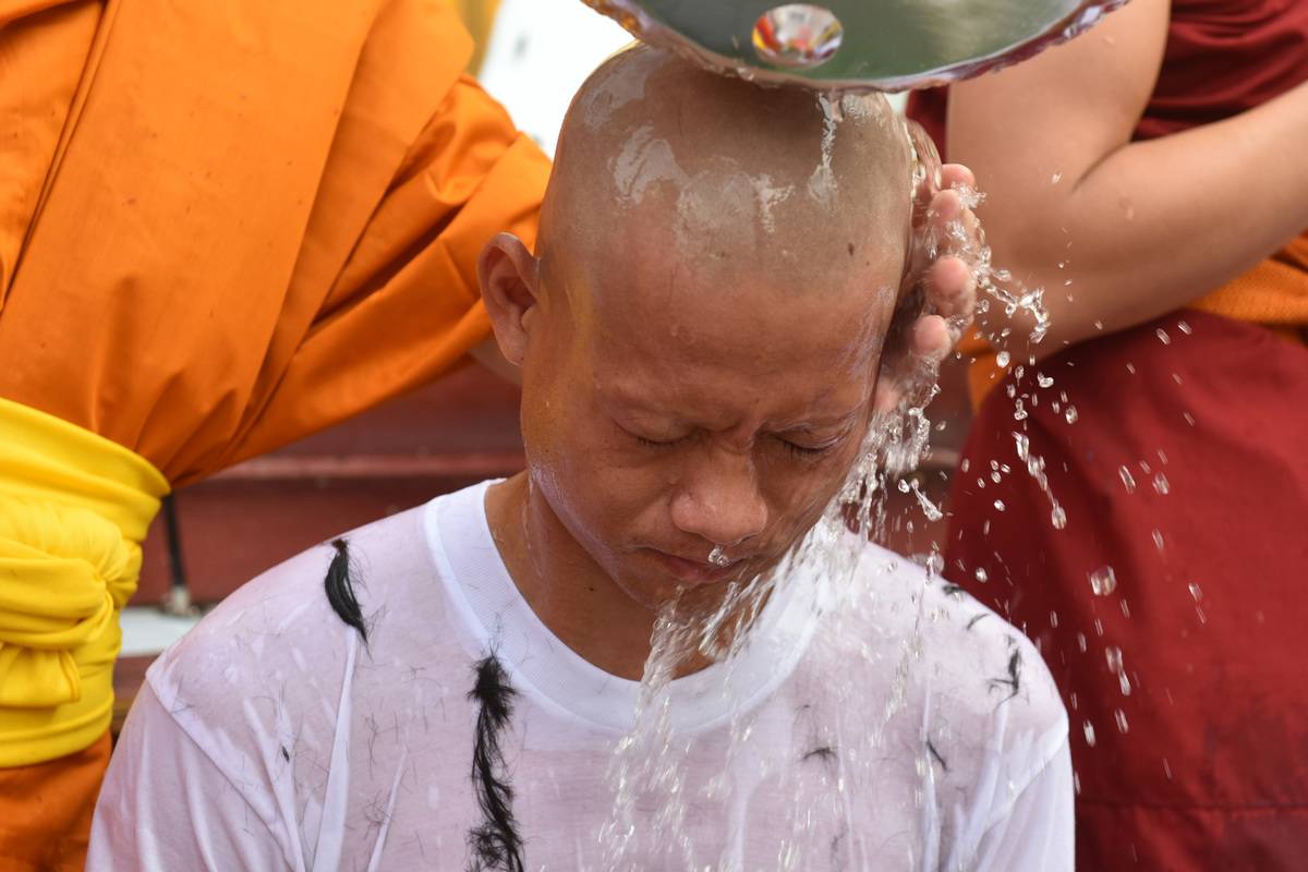 Buddhist monks bathe the shaved head of the rescued Thai boy