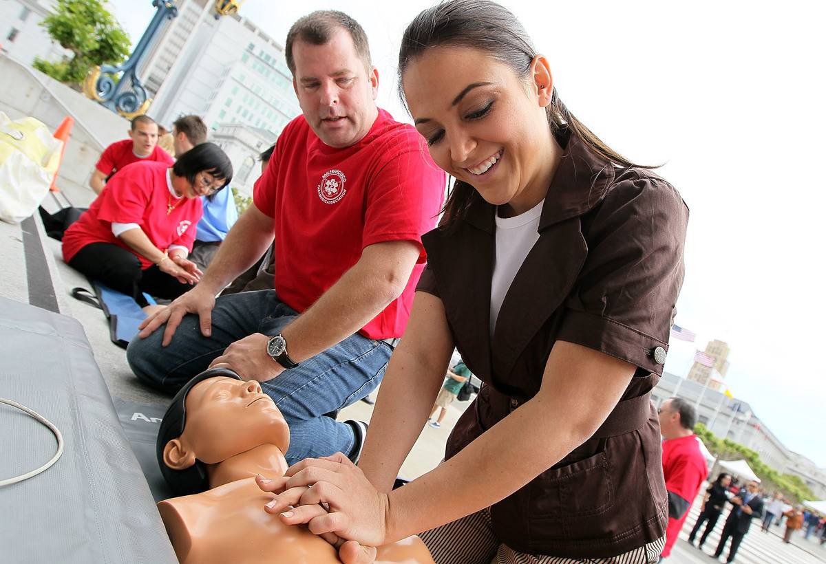 A woman performs chest compressions on a mannequin while learning C.P.R.