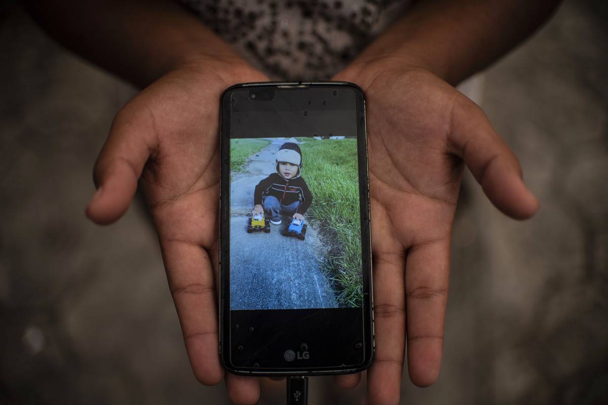 Honduran woman shows a picture of her son on her mobile phone