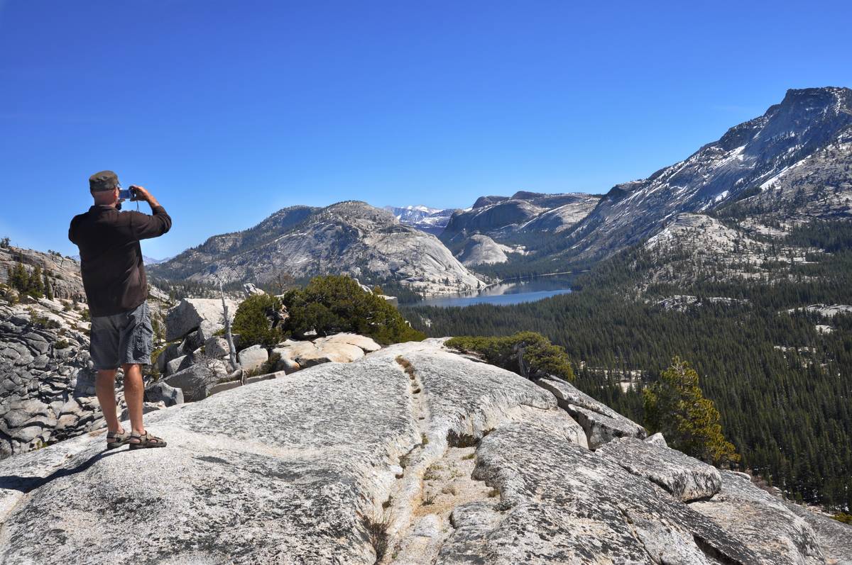 A visitor to Yosemite National Park in California admires the view of Tenaya Lake from Olmsted Point, a popular destination in the park featuring views of Yosemite Valley