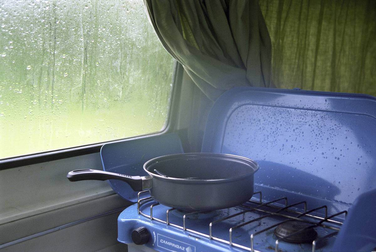 Cooking food on stovetop in a campervan on a rainy day in England