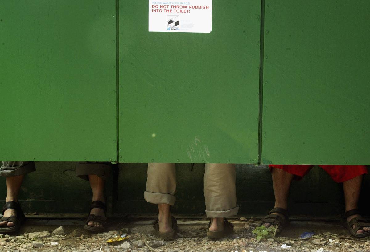 Festival-goers use neighboring toilet cubicle stalls